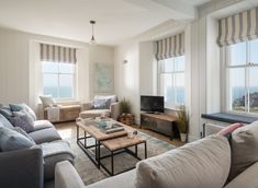 a living room with two couches and a coffee table in front of large windows