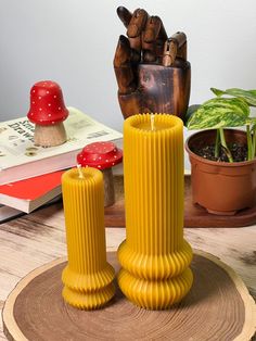 a yellow candle holder sitting on top of a wooden table next to a potted plant