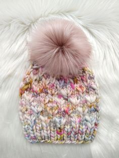 a multicolored knitted hat with a pom - pom on top