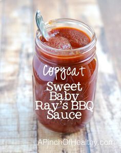 a glass jar filled with baby's bbq sauce on top of a wooden table