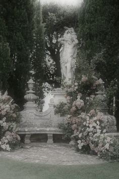 a statue surrounded by flowers and trees in black and white photo with color filter applied