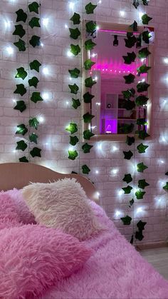 a bedroom with pink bedding and white lights on the wall, along with ivy covered walls