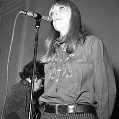 a woman standing in front of a microphone on top of a stage with another person behind her