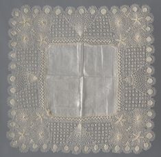 an old doily with white lace and flowers on the edges, in front of a gray background