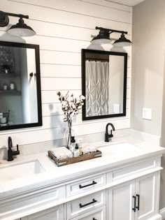 a bathroom with two sinks, mirrors and lights on the wall above them is shown