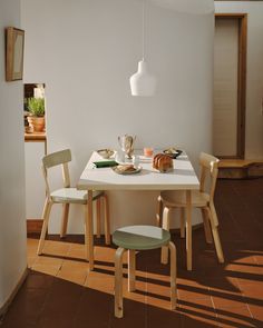 a white table and chairs in a room with brown tile flooring on the walls