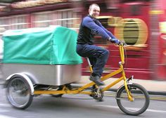 a man riding a bike with a cart on the back