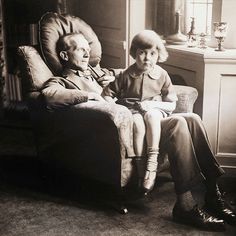 an old black and white photo of two people sitting on a chair in a living room