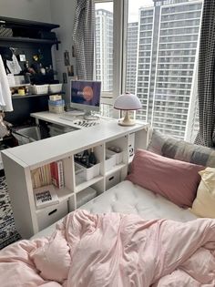 a bedroom with a bed, desk and computer on it in front of a window