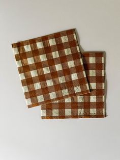 two brown and white checkered napkins sitting on top of each other