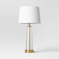 a lamp with a white shade on top of it and a gold frame around the base