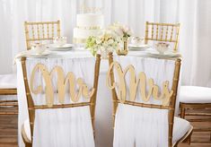 the table is set up with two chairs and a white cake on top of it