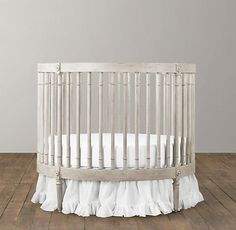 a baby crib with white bedding and wooden floors