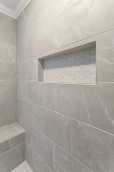 a white tiled bathroom with gray walls and floor tiles on the shower wall, along with an open window