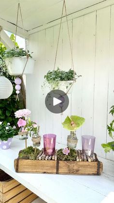 a table topped with lots of potted plants and hanging planters filled with flowers