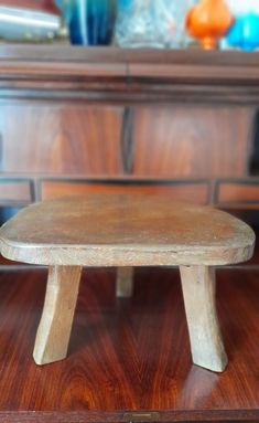 a small wooden bench sitting on top of a wooden table in front of a dresser