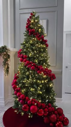 a christmas tree with red ornaments and lights in the shape of a ball on top