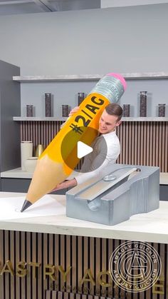 a man is holding a giant pencil in his hand