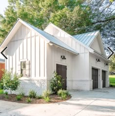 a white building with two garages on the front and one in the back side