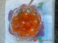 a glass bowl filled with oranges sitting on top of a towel next to a spoon