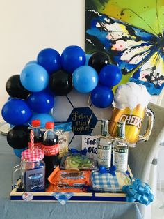 blue and black balloons are on the back of a chair next to a tray with drinks