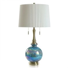 a blue glass lamp with a white shade on the base and a gold metal base