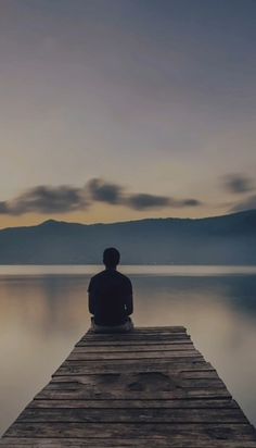 a person sitting on a dock looking out at the water