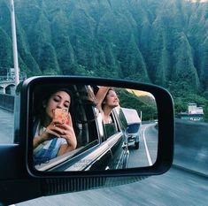 a rear view mirror on the side of a car with a woman taking a photo