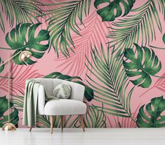 a chair in front of a pink wall with palm leaves on it and a lamp next to it