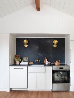 a kitchen with white cabinets and black backsplash is featured in an article from the magazine