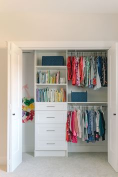 an organized closet with clothes, books and other items on shelves in the middle of it