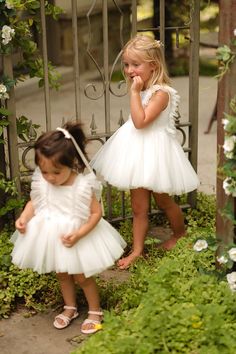 Dress your little princess in the Mini Fairy Garden Dress in White, a whimsical ensemble designed for enchanting adventures. Featuring a square neckline and cap-length ruffle sleeves, this dress boasts a knee-length skirt with a delicate crinoline underlay for extra flair. Complete with a hidden back zipper and a comfortable smocked back detail, it’s perfect for twirling through fairytale realms and making magical memories. Spring Fairy Dress With Ruffles For First Birthday, White Princess Baptism Dress With Ruffles, Princess Infant Dress, White Fairy Dress Baby, Princess Tutu Dress For Baptism - Spring Season, Thanksgiving Dress, Mini Fairy Garden, Garden Dress, Baby Fairy