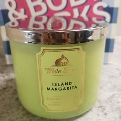 a candle that is sitting on a counter next to a sign with the words white barn island margaritaria