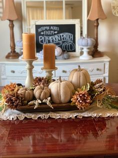 a table topped with candles and pumpkins on top of a wooden tray next to a mirror