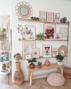 there are many pictures on the wall above the table and in front of it is a bench with potted plants