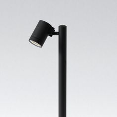 a black lamp with a white light on the top of it and a gray background