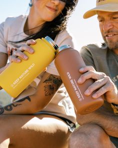 a man and woman sitting next to each other with water bottles in their hands on the ground