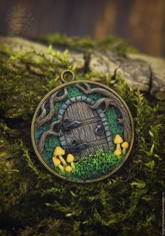 a necklace with an image of a door in the grass and mushrooms around it, on top of moss