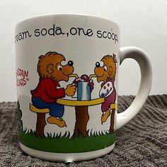 a coffee mug with two bears sitting at a table