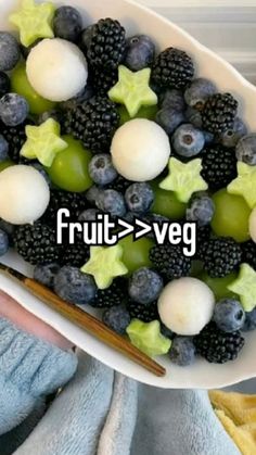 a white bowl filled with fruit next to a pair of chopsticks on top of a towel