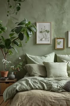 a bed with green sheets and pillows in a bedroom next to a potted plant