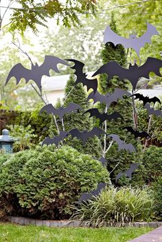 a group of metal bats hanging from the side of a tree in a yard next to bushes