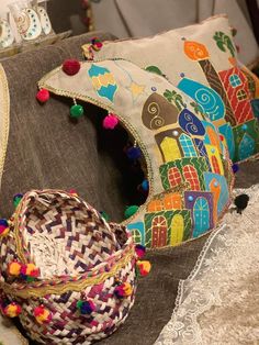 two woven baskets sitting on top of a table next to a pillow with pom - poms