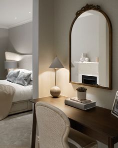 a bedroom with a bed, desk and mirror in it's corner area next to a fireplace