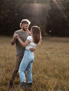 a man and woman are standing in the middle of a field with their arms around each other