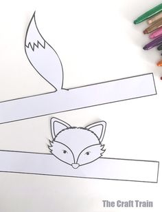 a paper cut out of a fox on a branch with crayons next to it