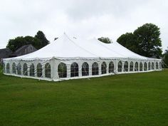 a large white tent sitting on top of a lush green field