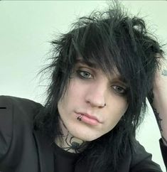 a man with black hair and piercings on his head is posing for the camera