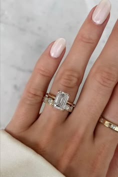 a woman's hand with two gold rings and a diamond ring on her finger