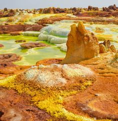 some yellow and green colored water with rocks on the ground in the foreground is a rock formation that looks like it's melting